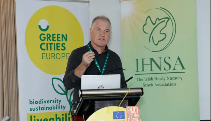 An image of the Guest Speaker standing behind a Podium giving a talk 