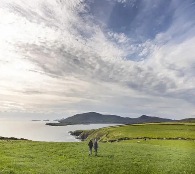 Landscape of the sea and cliffs with two farmers walking on a field