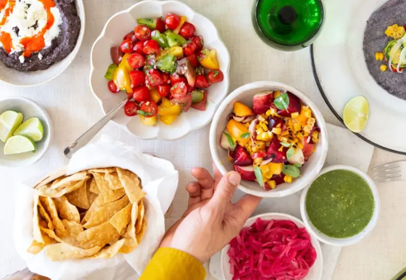 Hand reaching out for dips and tortilla chips